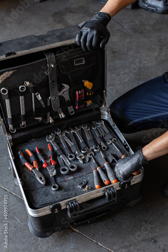 From above unrecognizable male technician picking screwdriver bits from tool box while working in garage