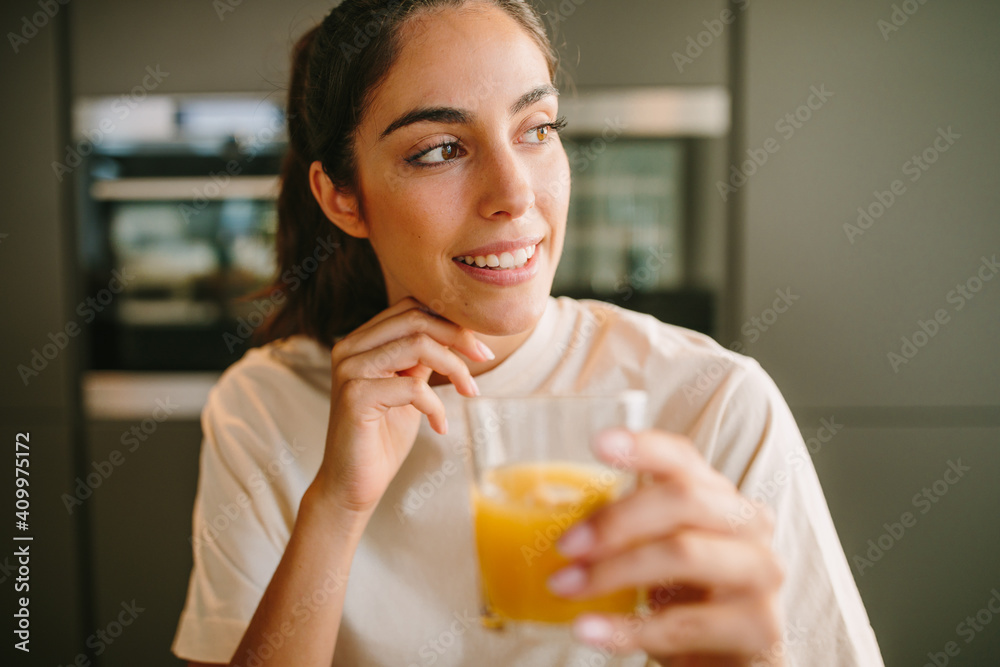 Peaceful female sitting at table with glass of orange juice at home Peaceful female sitting at table with glass of orange juice at home