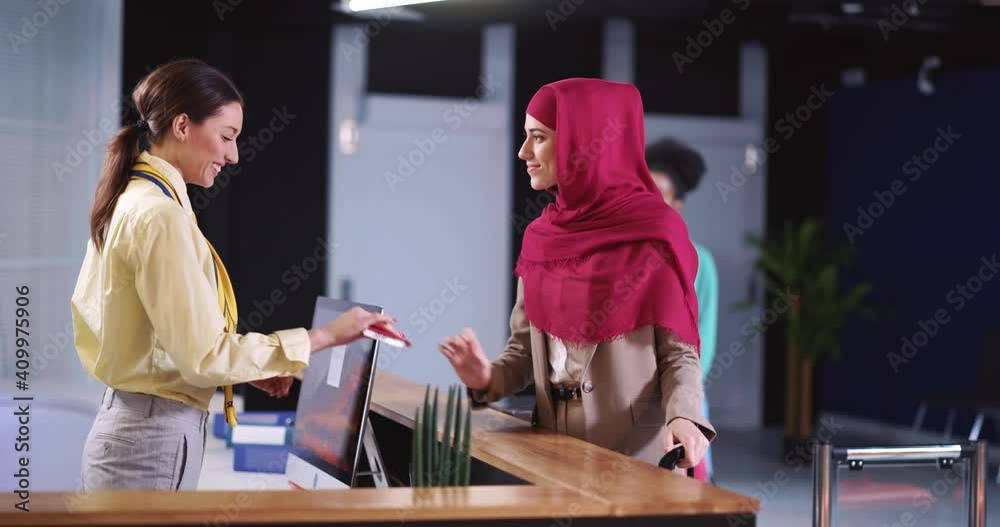Arabic young woman in hijab taking services at registration counter. Airport executive checking customer information on travel ticket using computer. Terminal concept.