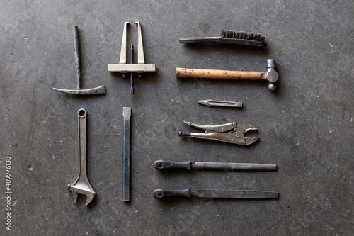 Top view of assorted shabby repair tools placed on grungy gray floor of workshop photo