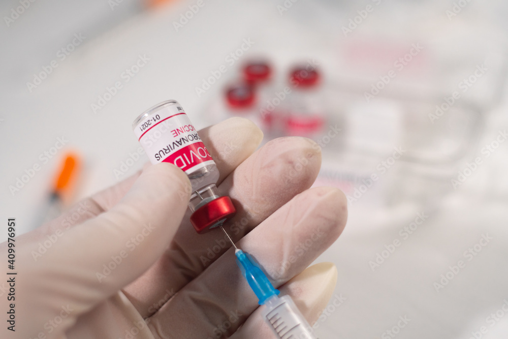 Closeup female doctor holds a syringe and a bottle of coronavirus vaccine. Concept of treatment of coronavirus infection, COVID-19 vaccination