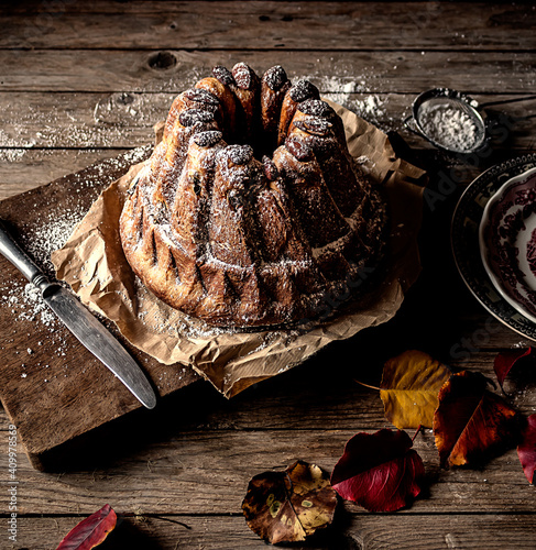 From above fresh tasty Kugelhopf on weathered wooden tabletop near dry autumn leaves