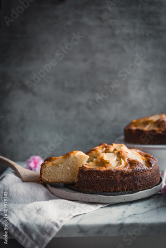 Composition of delectable homemade apple cakes on plates placed on table with bowl with sweet syrup and cooking brush
