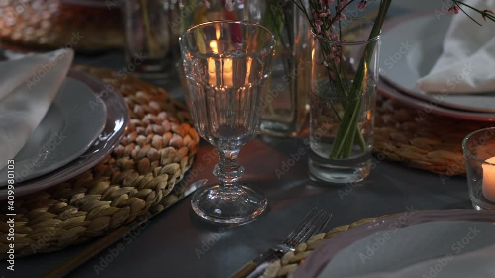 Table decorated with genista flowers and bergrass. Serving with wicker coasters for plates, napkins, burning candles and glasses. Decorations and table for wedding and dinner parties. Table decorated with genista flowers and bergrass. Serving with wicker coasters for plates, napkins, burning candles and glasses. Decorations and table for wedding and dinner parties.