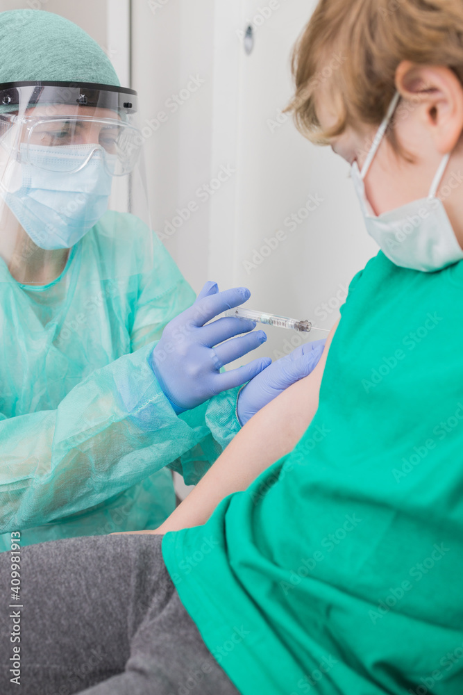 Medic in protective uniform and with sterile syringe giving injection for child from coronavirus Medic in protective uniform and with sterile syringe giving injection for child from coronavirus