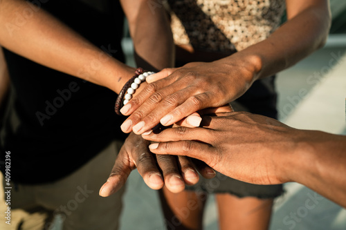 High angle of crop unrecognizable African American company of friends stacking hands together on street on sunny day