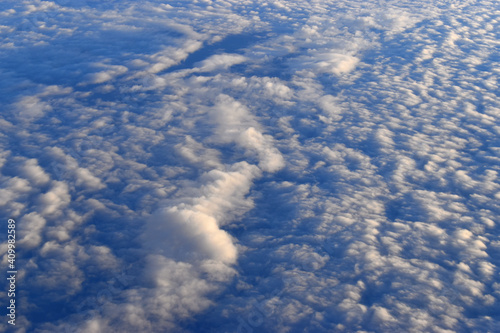 Dramatic sky with landscape of white clouds viewed from high altitude. Viewed from airplane window.