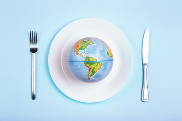 Globe on a plate for food on a blue background. Power, economy, politics, globalism, hunger, poverty and world food concept
