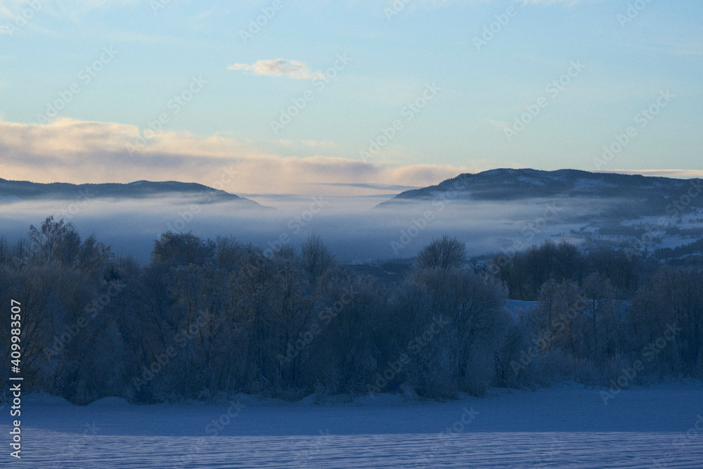 View toward the Totenåsen Hills from the rural lowlands of Toten, Norway, a frosty winter morning by sunset.