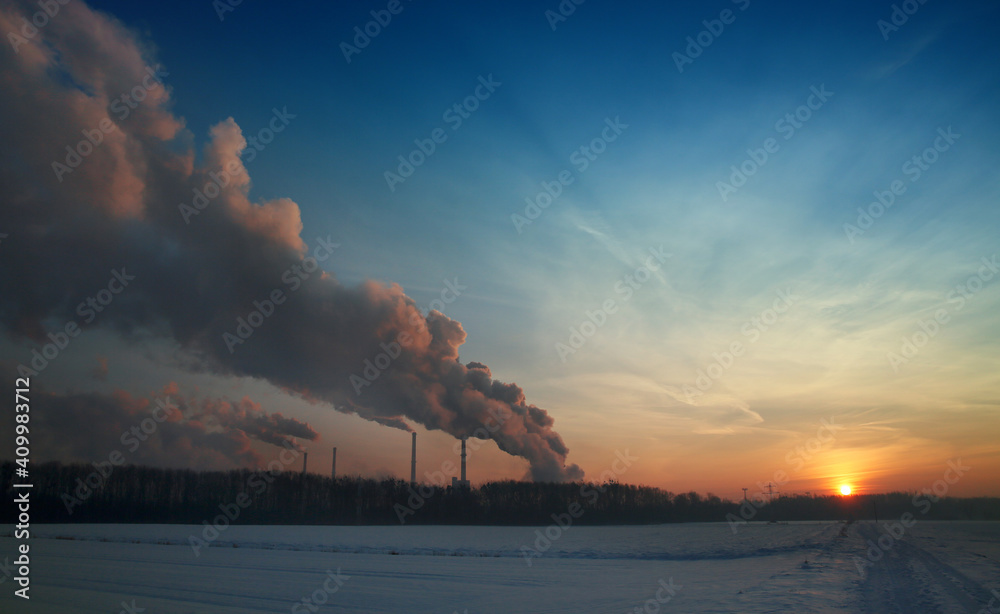 Steam from the factory at sunrise in winter 