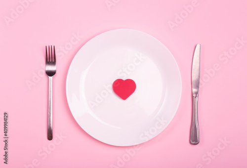 Heart on an empty plate on a pink background. Minimal art creative concept. Red heart as a symbol of love, romance and "like" idea.