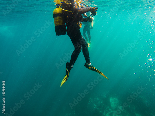 Cropped unrecognizable divers scuba diving in deep ocean photo