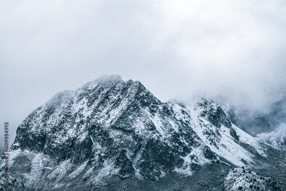 Majestic panoramic scenery of rough rocky slopes of mountain range covered with snow under cloudy sky Majestic panoramic scenery of rough rocky slopes of mountain range covered with snow under cloudy sky