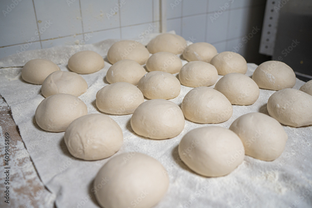Raw buns of dough ordered on table and prepared for cooking in kitchen of bakehouse Raw buns of dough ordered on table and prepared for cooking in kitchen of bakehouse