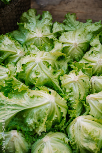 From above of basket with heap of fresh organic green iceberg lettuce placed on stony ground on agricultural market