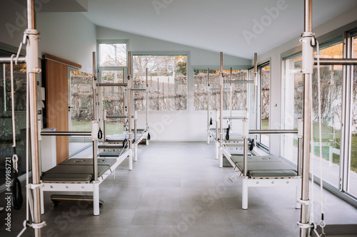 Bright interior of gym with contemporary pilates reformers placed in spacious facility for workouts photo