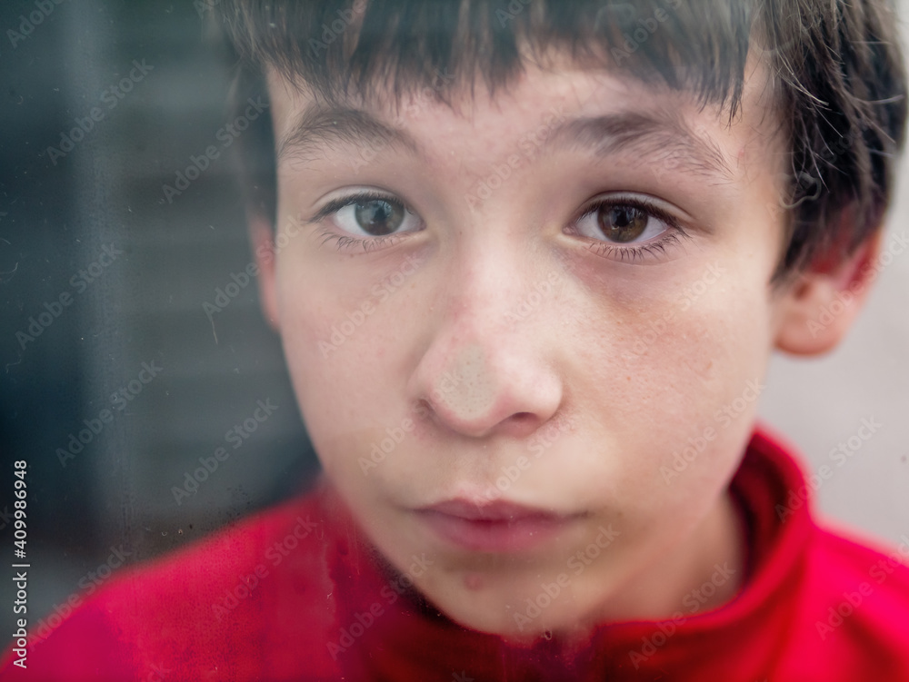 Teenage presses his nose against a window pane Teenage presses his nose against a window pane