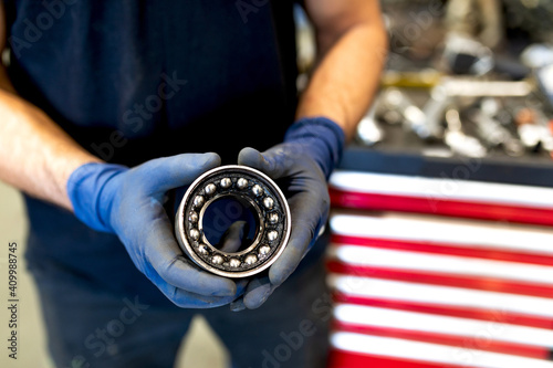 Unrecognizable crop male technician standing with round detail of car bearing in modern service