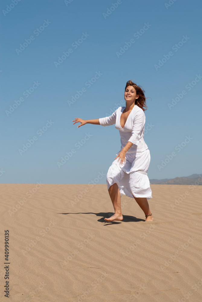 woman dressed in white enjoying in the sand dunes on the sunny day woman dressed in white enjoying in the sand dunes on the sunny day