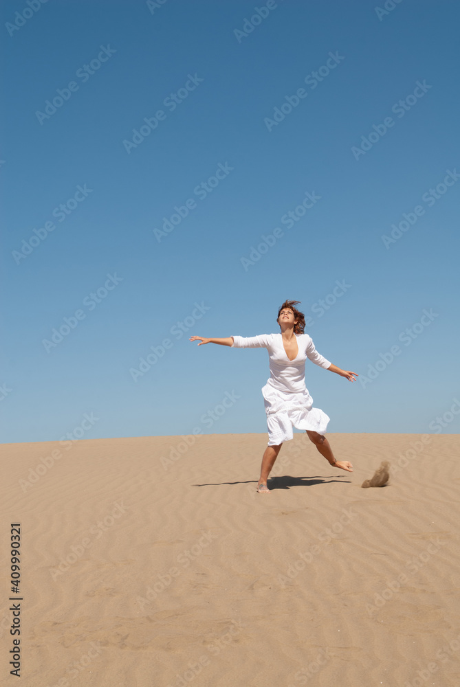 woman dressed in white enjoying in the sand dunes on the sunny day woman dressed in white enjoying in the sand dunes on the sunny day