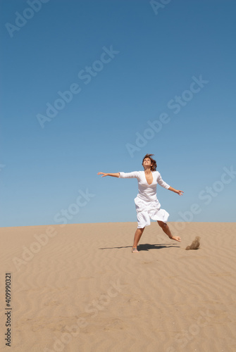 woman dressed in white enjoying in the sand dunes on the sunny day
