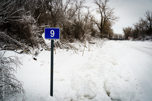 Road sign in the ice ninth kilometer. Snowy road, photo