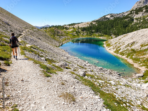 Quadro em tela Female hiker hiking along crystal clear mountain lake.