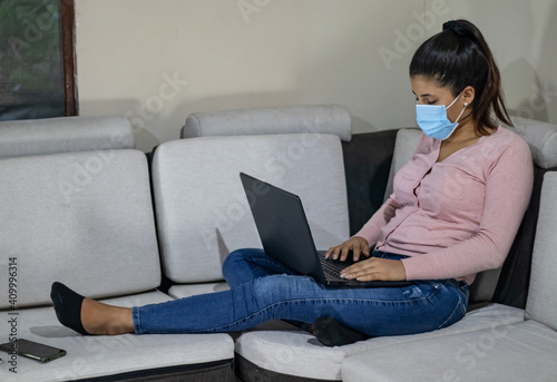 Young woman working from the sofa at home due to covid 19