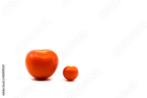 Small cherry tomato side by side with large tomato. Compare concept. Copy space. No people.