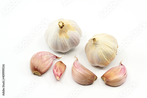 Close up of cloves and bulbs of fresh garlic or "Allium sativum" on a plain white background. No people. Copy space.