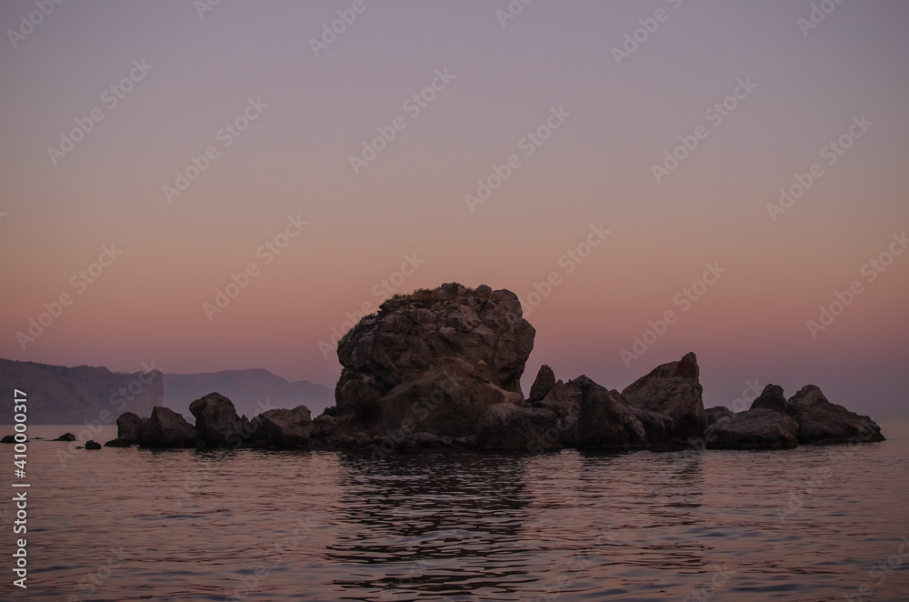 sunset over the sea, rock in the sea, lilac landscape

