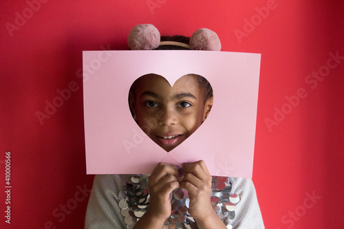Portrait of a girl with a paper heart on color background	