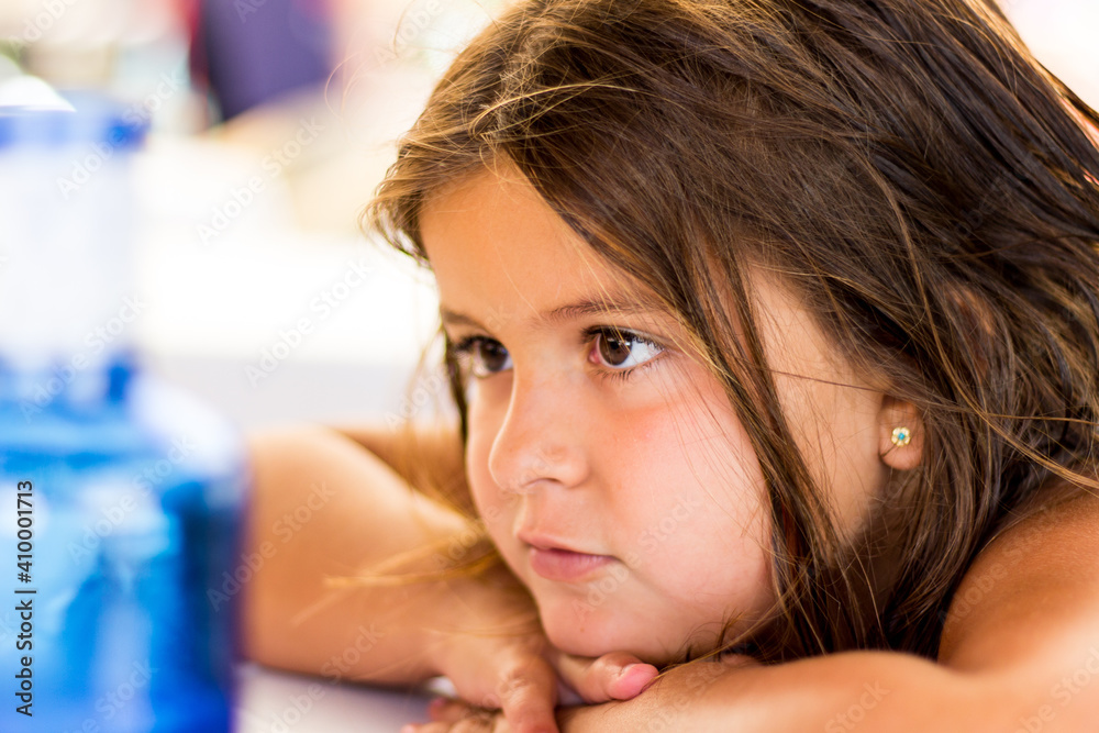 girl pensively at table next to water bottle girl pensively at table next to water bottle