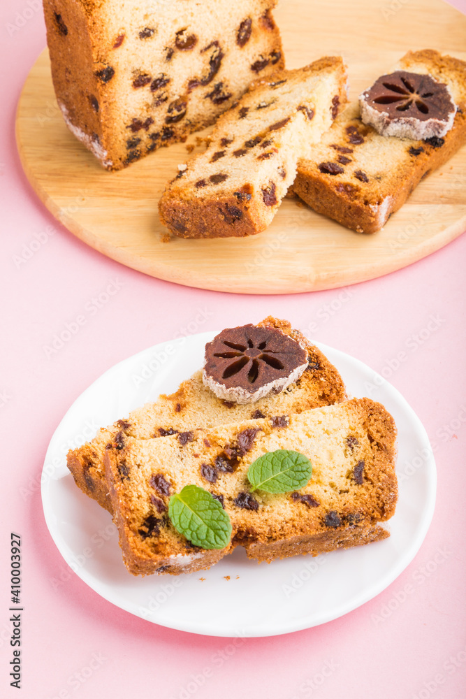 Homemade cake with raisins and dried persimmon on a pink pastel background. Side view, copy space.