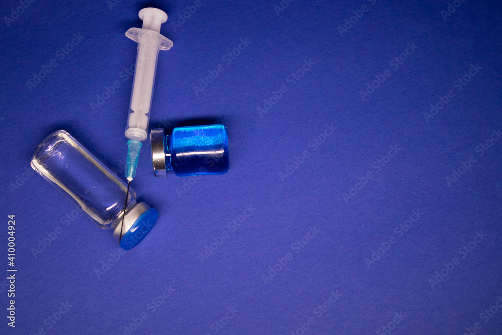 two transparent Vaccine bottle phial with no label, medical syringe injection needle. isolated on blue background. Development of coronavirus vaccine COVID-19. cure. World race in researching two transparent Vaccine bottle phial with no label, medical syringe injection needle. isolated on blue background. Development of coronavirus vaccine COVID-19. cure. World race in researching
