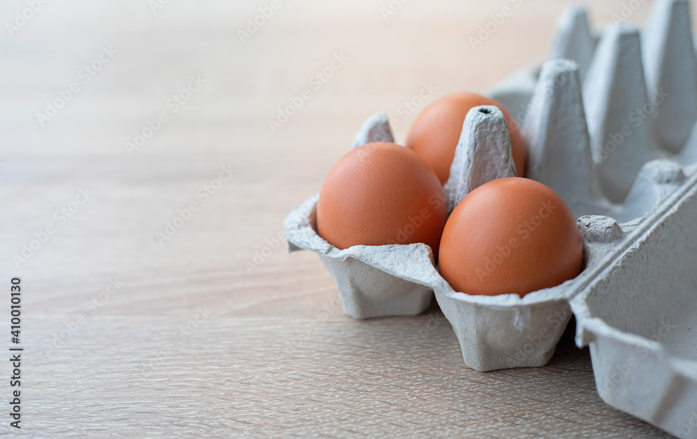 A carton of three fresh red free range eggs on a wooden table A carton of three fresh red free range eggs on a wooden table