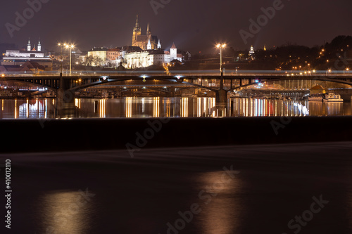 .panoramic view of Prague Castle and St. Vitus Cathedral and the Vltava River and street lights on bridges at night in the center of Prague © svetjekolem