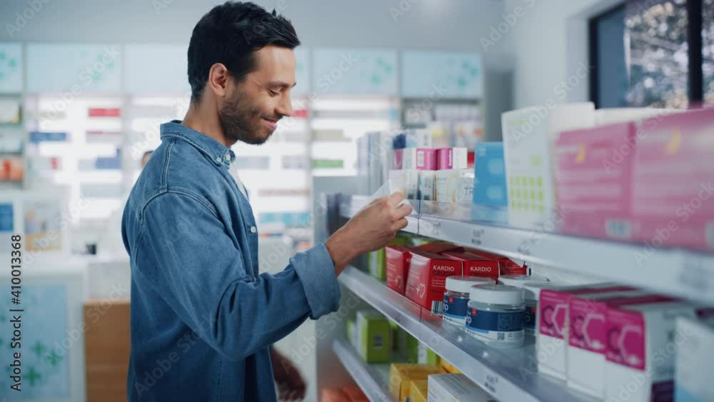 Pharmacy Drugstore: Portrait of Handsome Latin Man Choosing to Buy Medicine Browsing through the Shelf, Successfully finds what he Needs, Smiles Happily. Modern Pharma Store Health Care Products Pharmacy Drugstore: Portrait of Handsome Latin Man Choosing to Buy Medicine Browsing through the Shelf, Successfully finds what he Needs, Smiles Happily. Modern Pharma Store Health Care Products