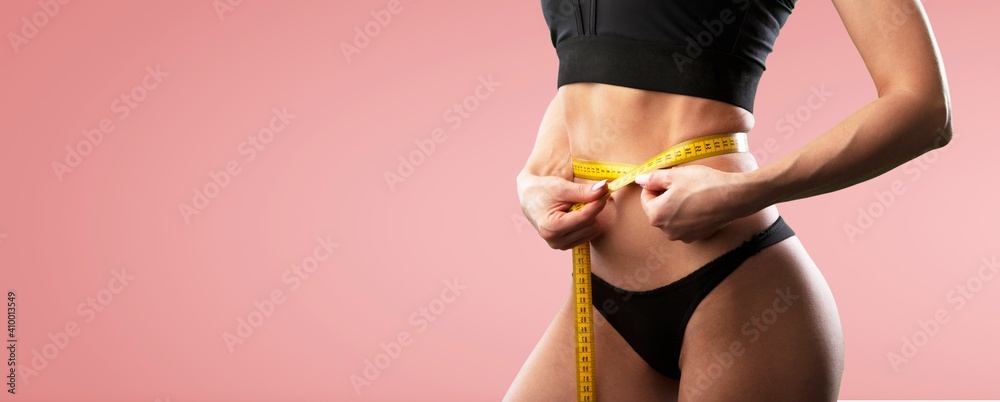 Beautiful fitness girl measuring her waistline with measure tape - obrazy, fototapety, plakaty 