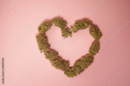 Heart shape cannabis buds. Pink background. Medical marijuana greeting card. Valentines day wallpaper