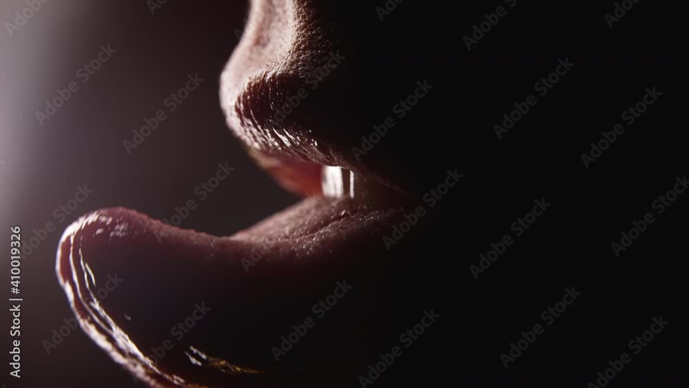 Close-up of woman's mouth. She shows her tongue seductively and licking lips with desire. Temptation, hint and flirt concept