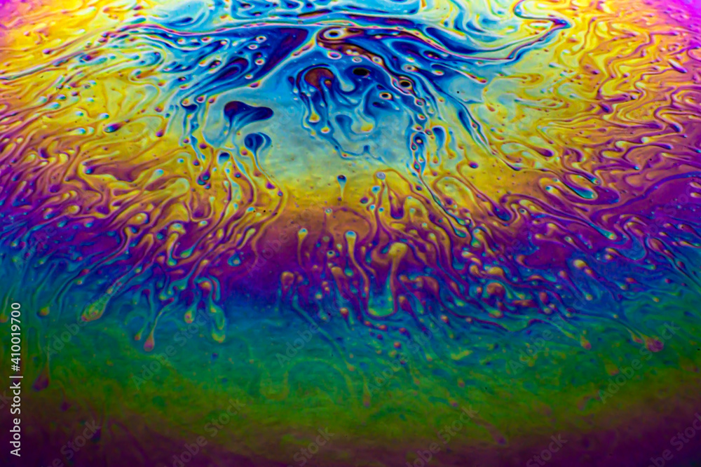 Macro soap bubble with purple, yellow, green, blue rainbow colors on black background. Looks like an abstract planet, galaxy, space background. 