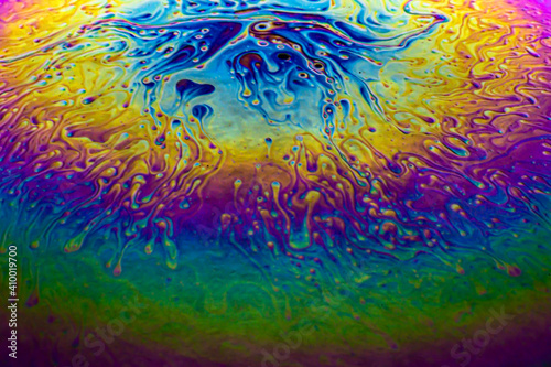 Macro soap bubble with purple, yellow, green, blue rainbow colors on black background. Looks like an abstract planet, galaxy, space background. 