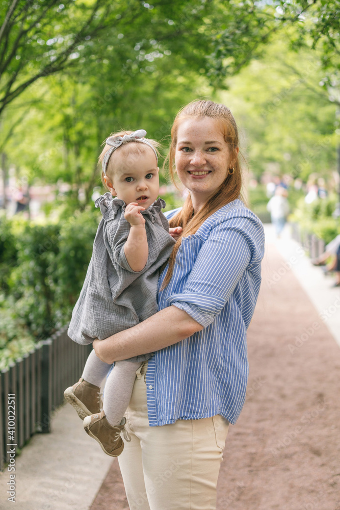 Fototapeta premium A young mother walks with a one-year-old baby. What to do while walking with your child