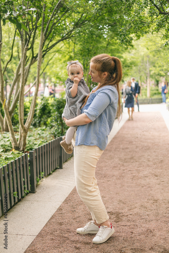 A young mother walks with a one-year-old baby, holds him in her arms, hugs. Communication with the child for his harmonious development A young mother walks with a one-year-old baby, holds him in her arms, hugs. Communication with the child for his harmonious development