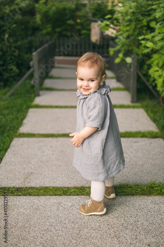 One year old baby girl in the mousline dress on the path in the park