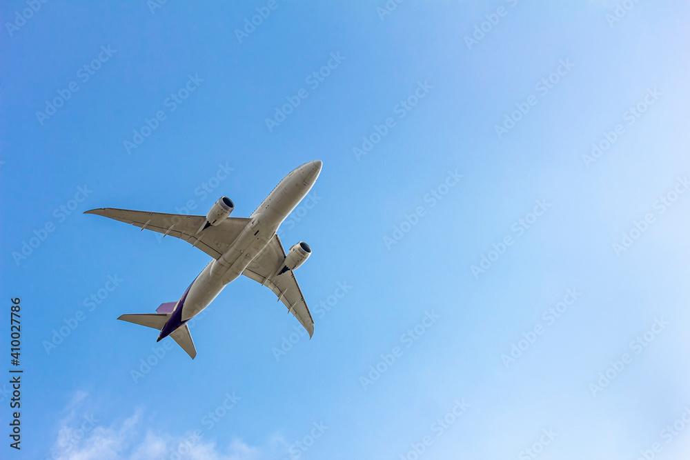 Under view of airplane for commercial passenger or cargo transporation flying on blue sky background with copy space Under view of airplane for commercial passenger or cargo transporation flying on blue sky background with copy space
