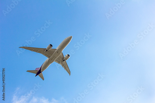 Under view of airplane for commercial passenger or cargo transporation flying on blue sky background with copy space