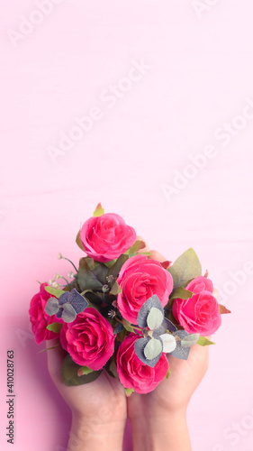 Hand holding red rose flower bouquet on pink background, Valentine day