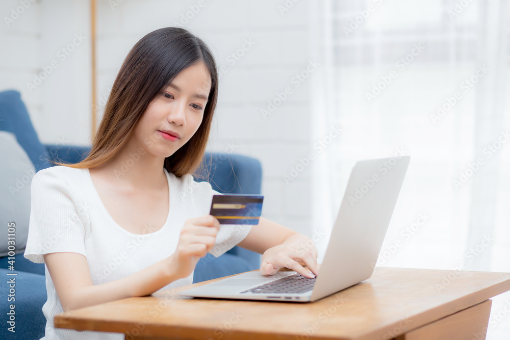 Young asian woman sit on sofa using laptop computer shopping online with credit card buying to internet, happy girl payment with e-business on couch, purchase and payment, business concept. Young asian woman sit on sofa using laptop computer shopping online with credit card buying to internet, happy girl payment with e-business on couch, purchase and payment, business concept.